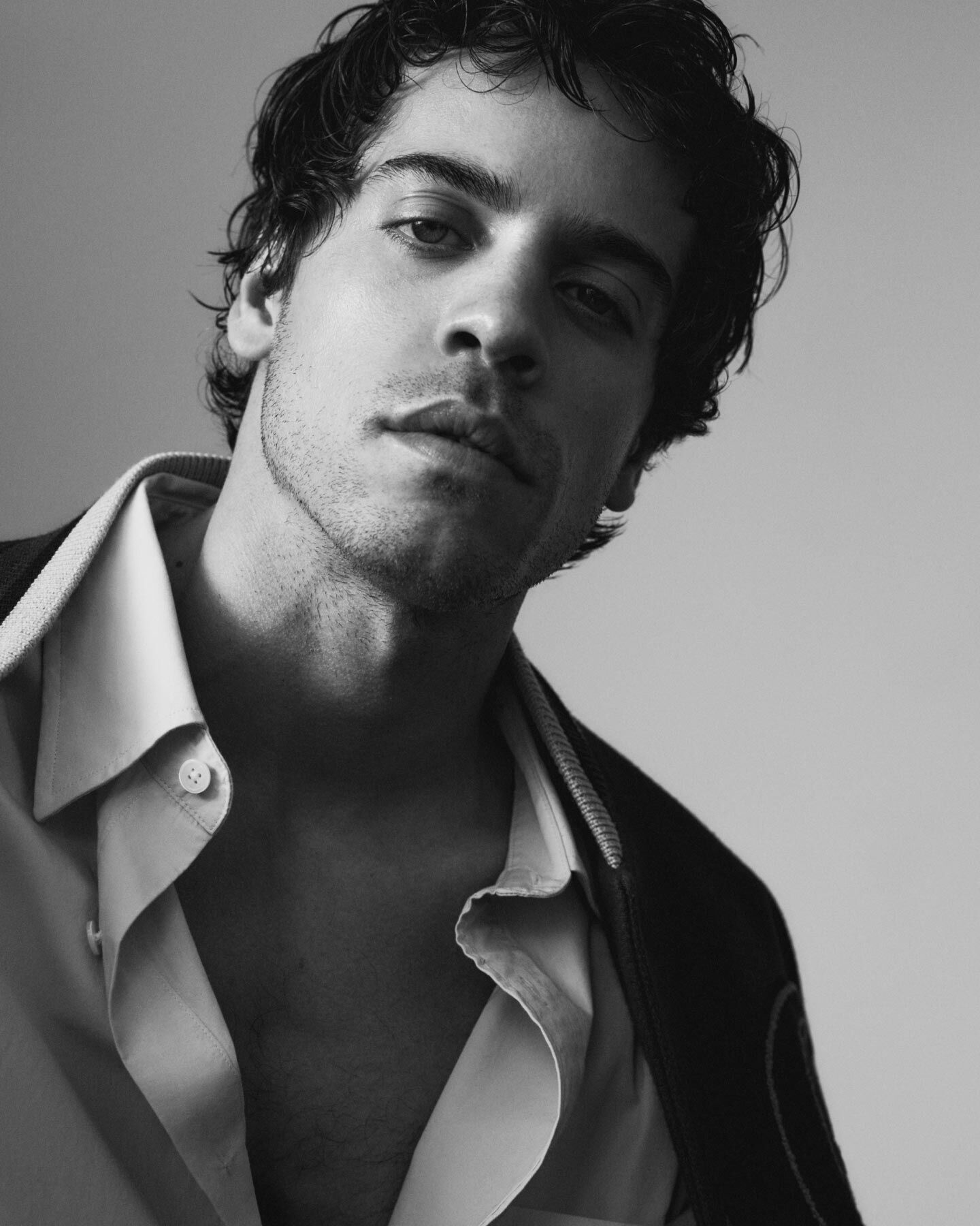 Ein Bild des spanischen Schauspielers Alex Pastrana, der ein Hemd und eine College-Jacke tr&auml;gt.