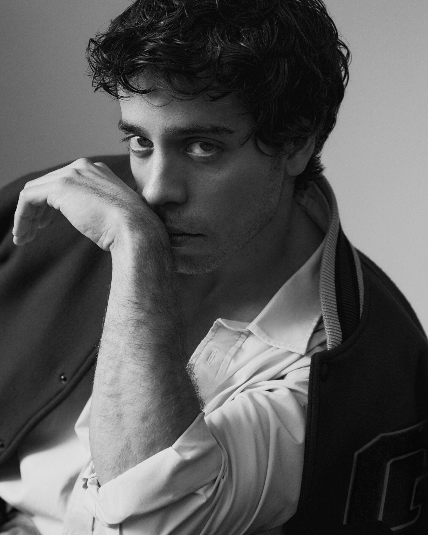 Ein Bild des spanischen Schauspielers Alex Pastrana, der ein Hemd und eine College-Jacke tr&auml;gt.